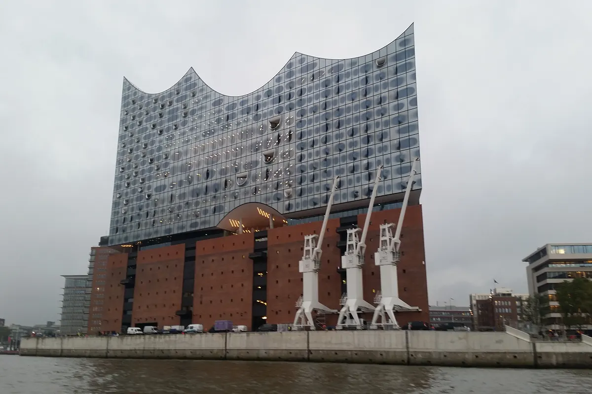 Die Elbphilharmonie in Hamburg mit ihrer markanten Glasfassade und den historischen Kränen am Hafen.